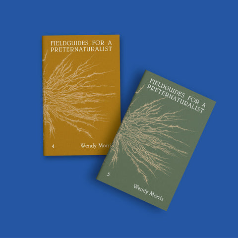 Two paperback books titled "Fieldguides for a Preternaturalist" by Wendy Morris are shown on a solid blue background. One book has a mustard yellow cover with a beige root-like illustration, and the other has an olive green cover with the same beige illustration.