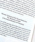 A close-up of printed text on a book or magazine page, with the title 'Mimetic Violence & Anti-Social Networks: The "Business of Hate" & the Industrialization of Friendship' visible.