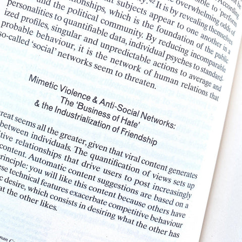 A close-up of printed text on a book or magazine page, with the title 'Mimetic Violence & Anti-Social Networks: The "Business of Hate" & the Industrialization of Friendship' visible.